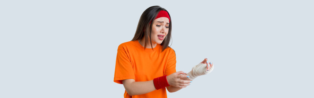 Woman in orange shirt applies bandage on wrist, visit Express ER in Temple Texas for injuries.